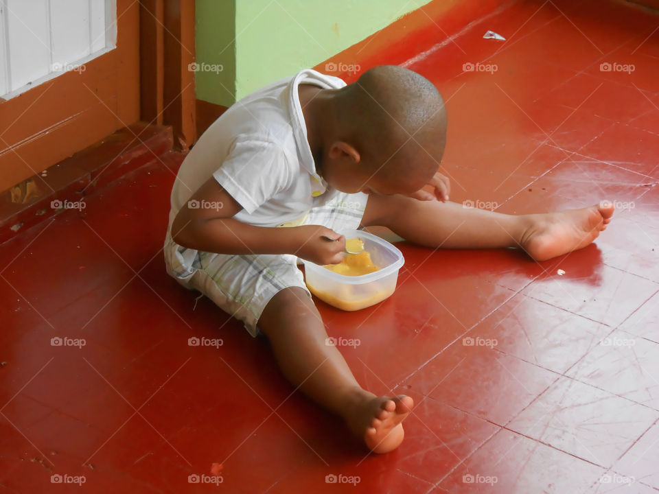 Boy Sitting On Floor To Eat
