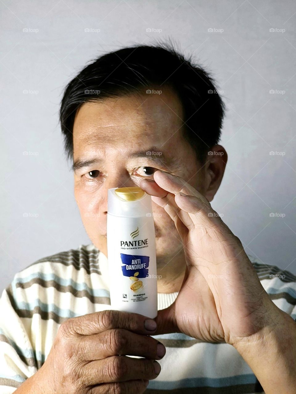 A Chinese man holding a shampoo.