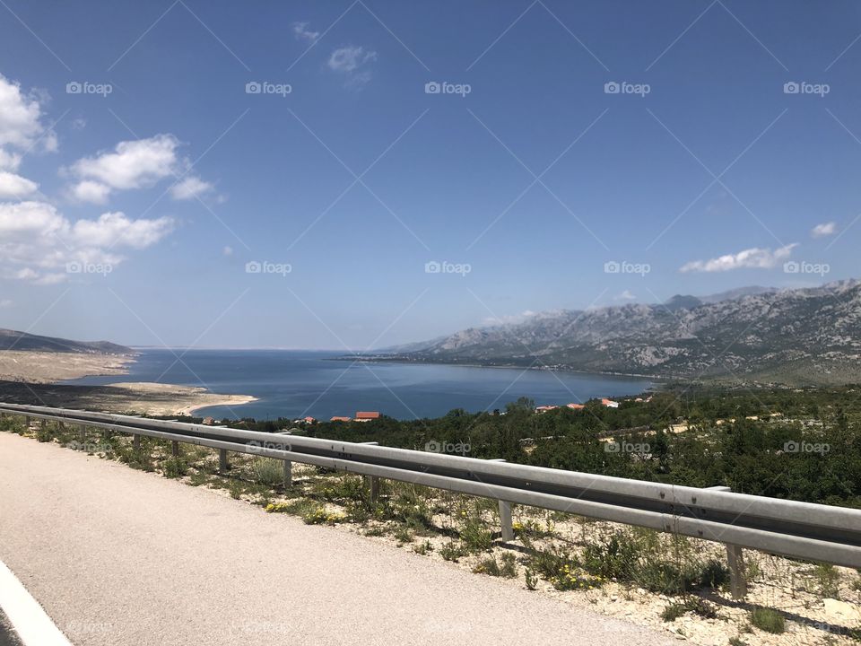 A road going through beautiful views of a lake in the distance large breathtaking mountain views