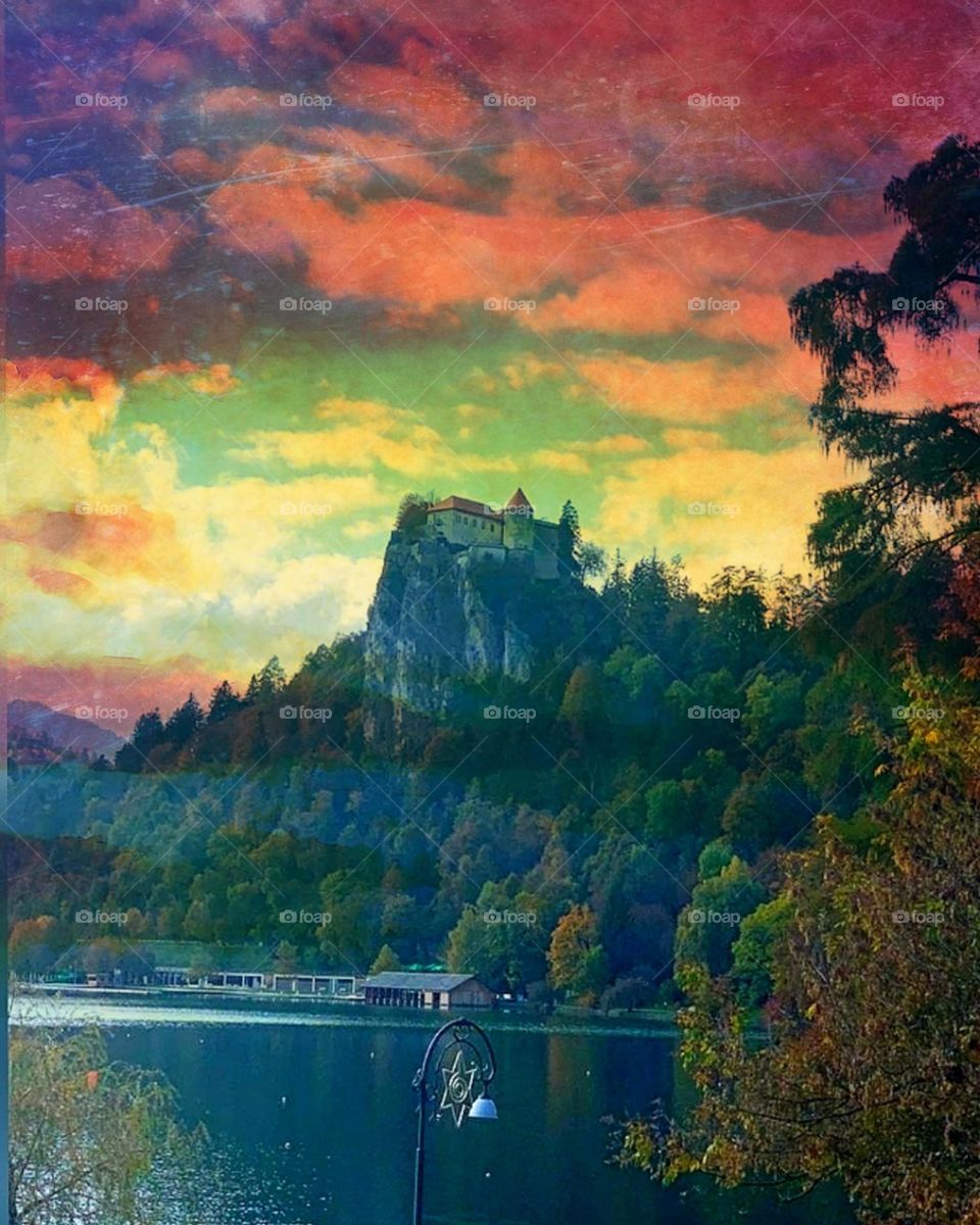 Village or city. Spaces of nature. Lake Bled (Bleysko). Bled Castle stands on a steep green rock. Slovenia. Sunset, lake, mountain, castle