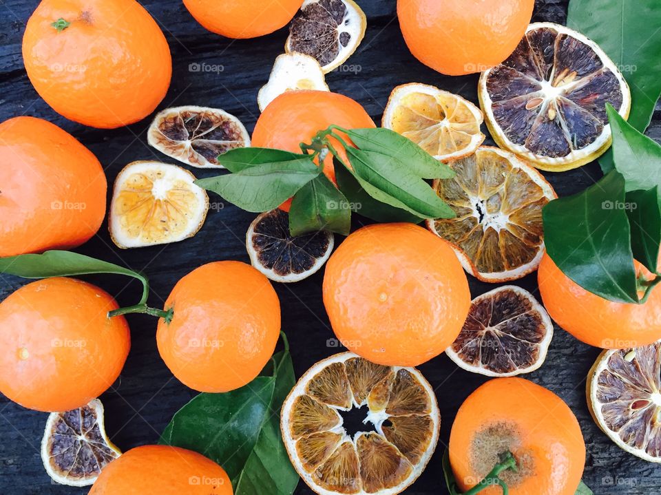 Mandarines with leaves and orange slices on wooden table 