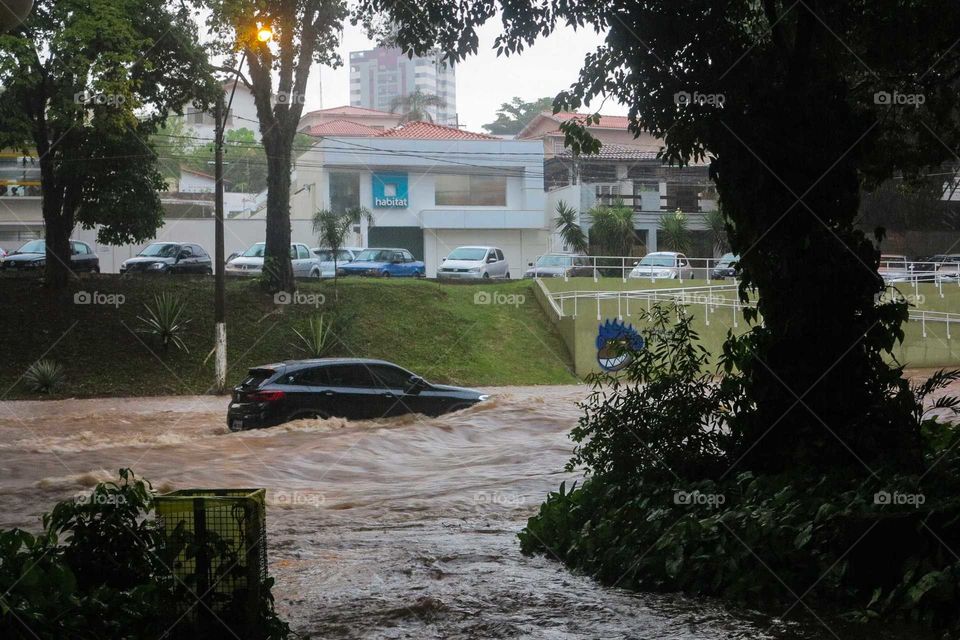 Car on a heavy rain day, on a flood, flooded street at Piracicaba, Brasil. 
Black car on the Waters of a flood in Brazil.