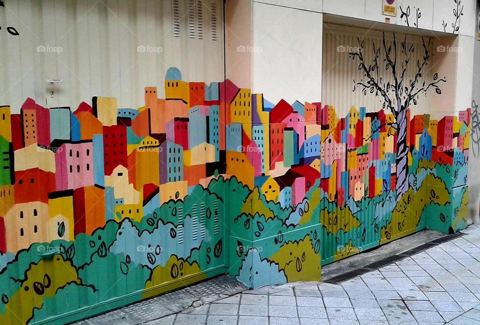 Street mural stretches down the side of a building and creates a colorful scene.