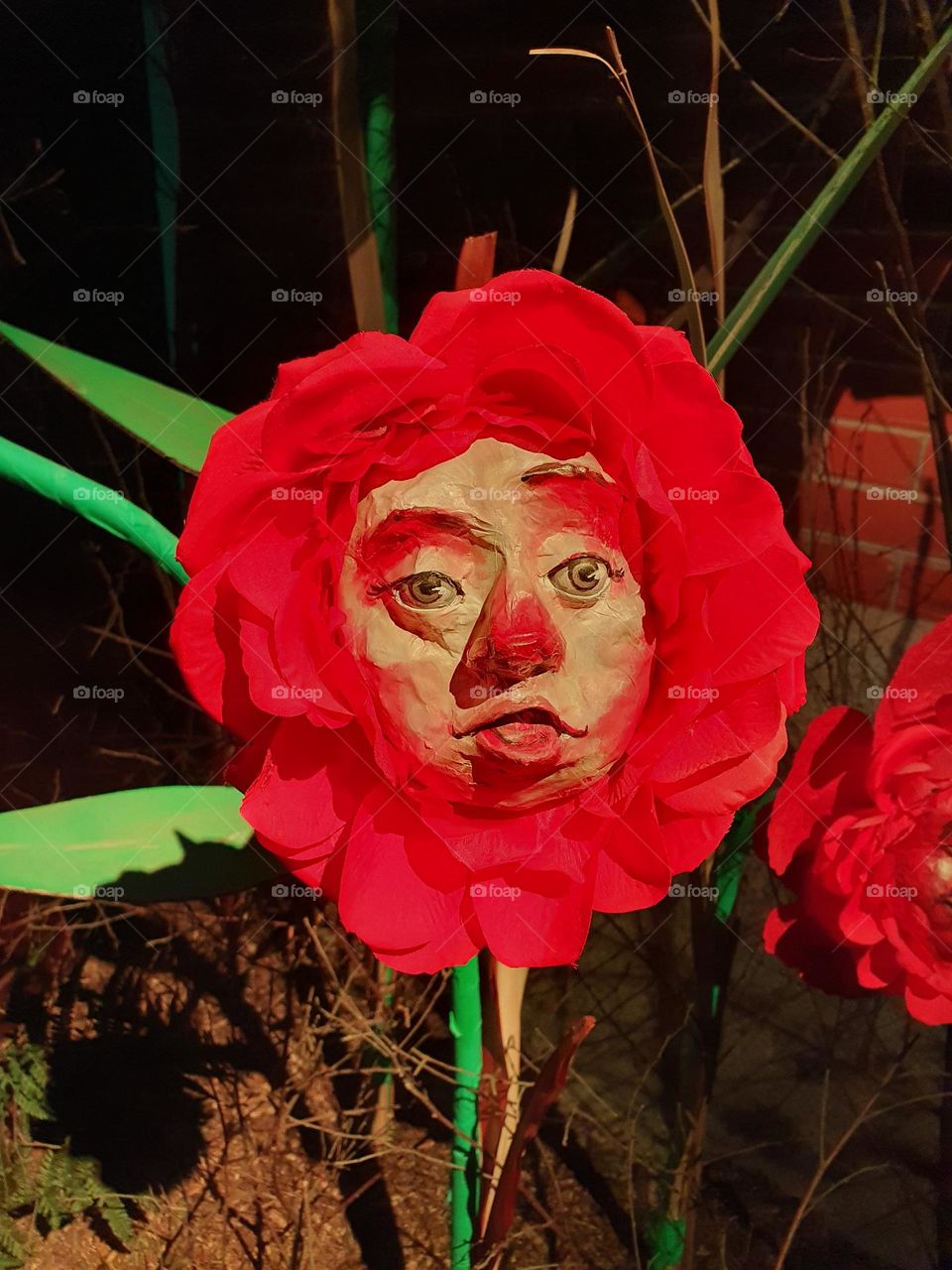 Close up on a paper handmade creation of a red flower with green leaves representing a funny face at a Christmas display in Suscinio's castle