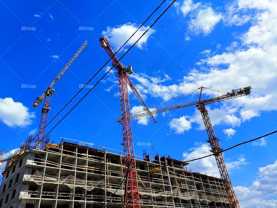 Home construction.  Three cranes near a house under construction