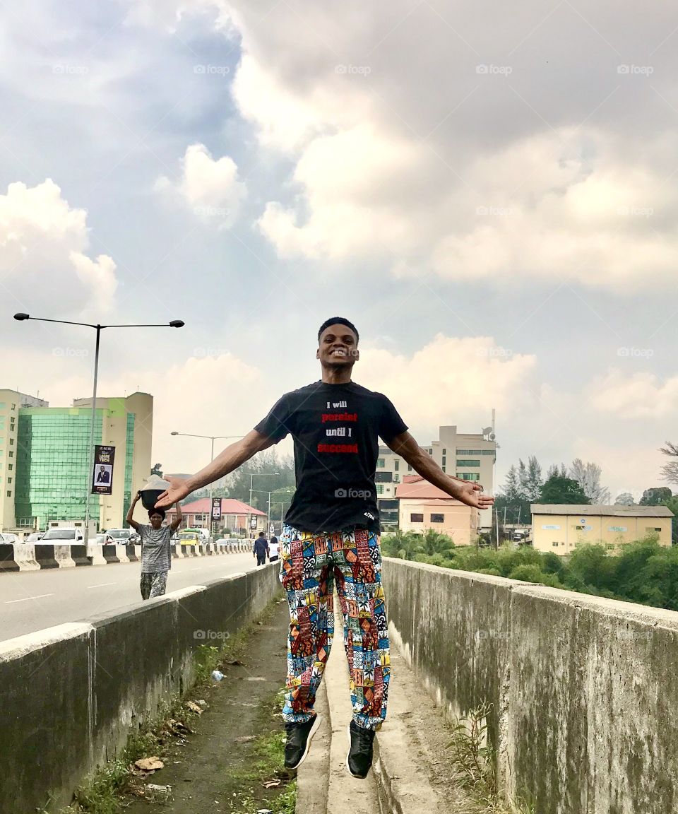 A man jumping in joy on a bridge in urban Africa 