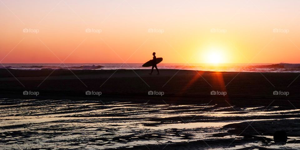 Surfer on the beach at sunset