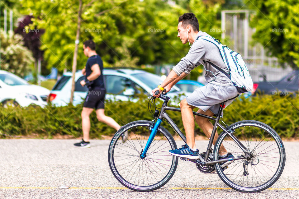 Young Man Riding Bike In City And Listening Music With Earphones
