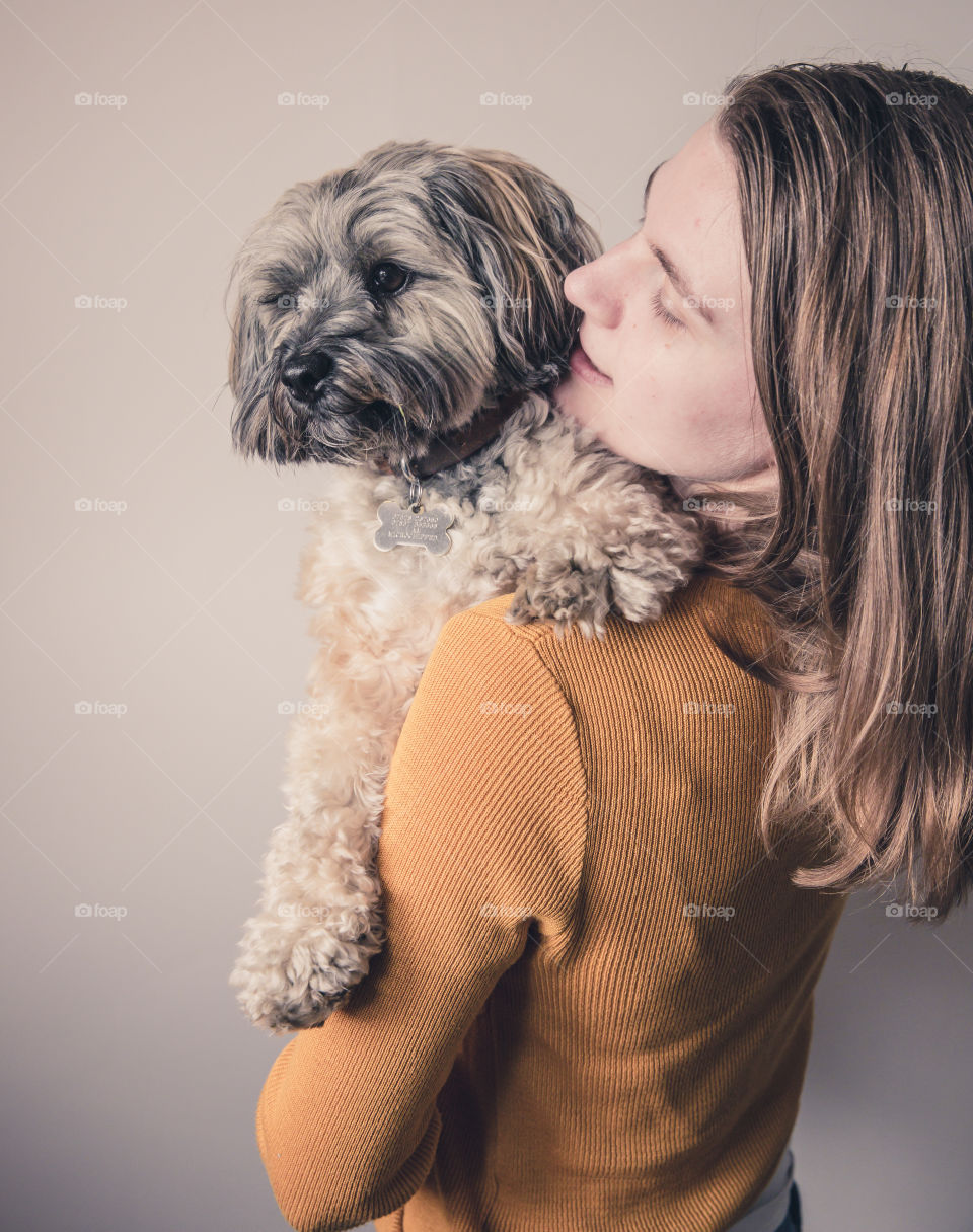 A pretty girl holding and cuddling her cute pet dog indoors