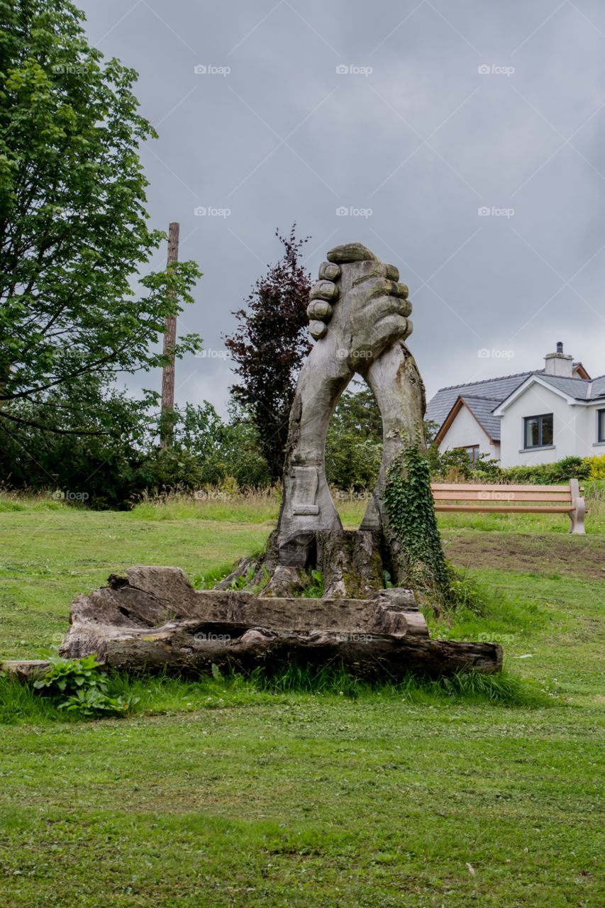 Two hands holding each other carved out of a tree 