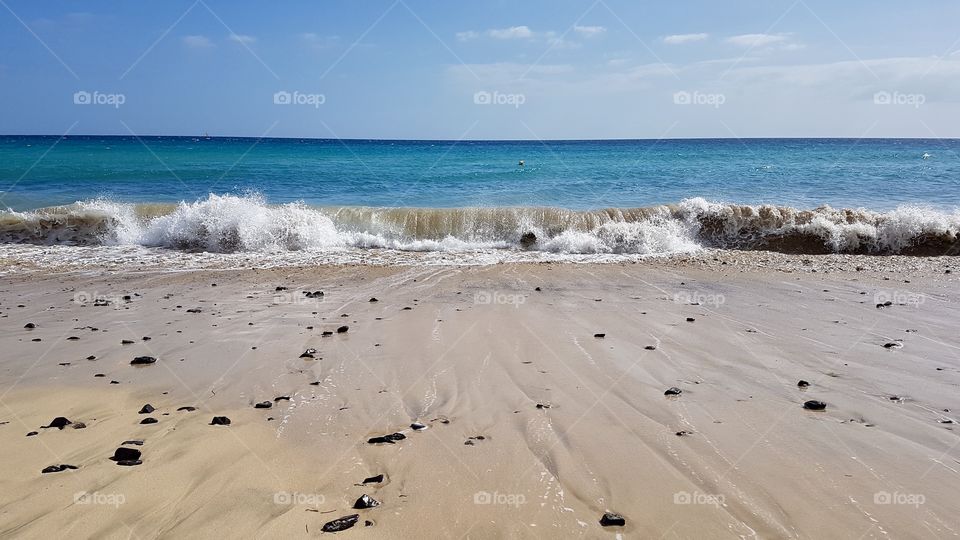 Sandy beach and waves in sunny weather, vacation in Fuerteventura Canary Islands Spain - fin sandstrand och vågor i soligt väder på Kanarieöarna Spanien