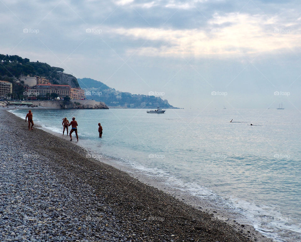 Elderly men playing with a ball on the pebble beach in Nice, France on an early fall morning.