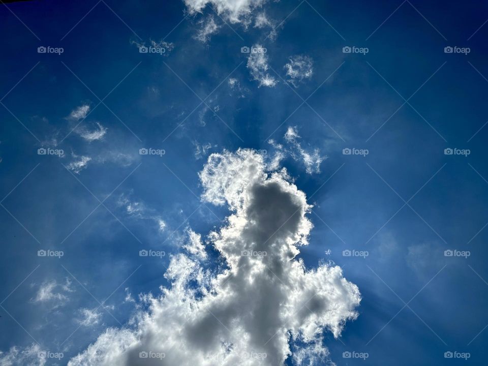 Beautiful clouds covering the sun on the blue sky while the sunbeams comes out from the clouds.