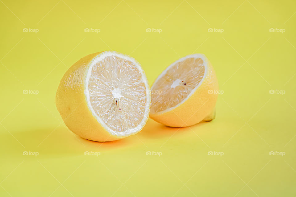 Halves of lemon on yellow background with  copy space.