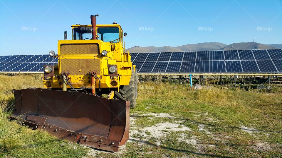 big yellow bulldozer, solar panels in the background