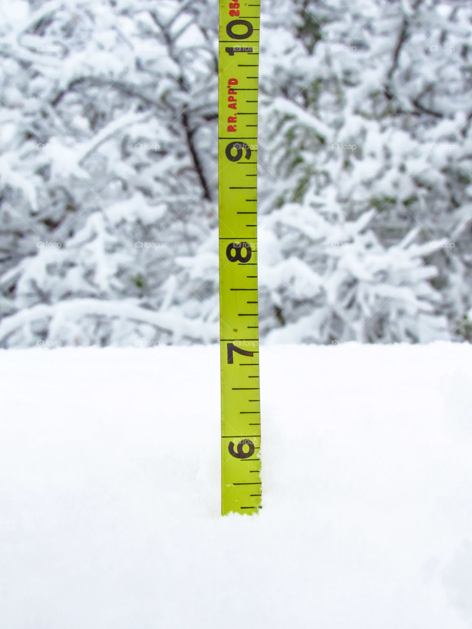 yellow tape measure measuring amount of snow fall