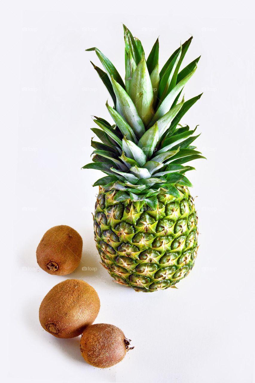 Pineapple and kiwi fruits with white background