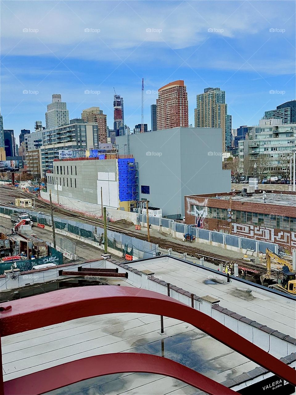 This is the view from the top of the red metal staircase of the “Pulaski Bridge” on the LIC side onto the “Long Island Railroad” tracks and the rectangular building that houses the “iFly” flight simulator. 2024. Hypnotic Productions