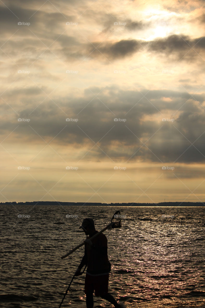 Silhouetted Man At The Beach Toting Metal Detector