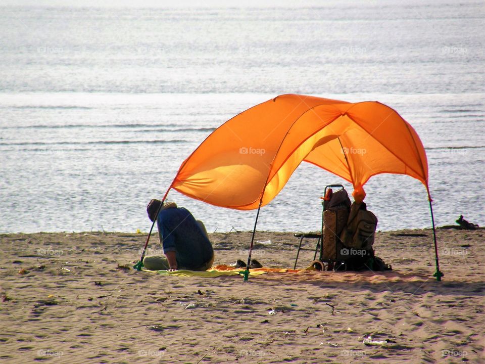 Man with orange tent at the beach next to the sea, Italy