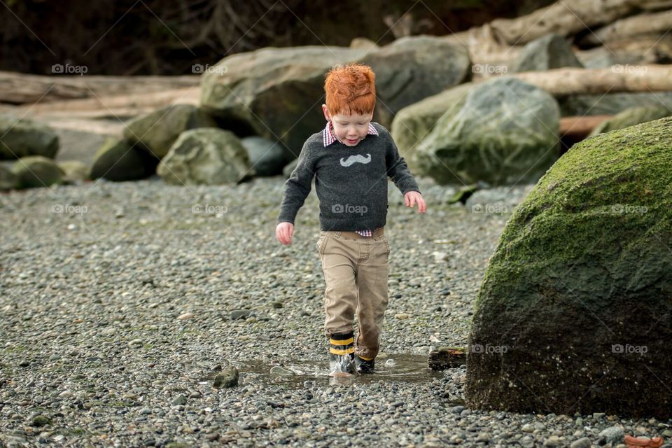 Toddler splashes in puddle at the beach. Mount Douglas park, Vancouver Island, Canada 