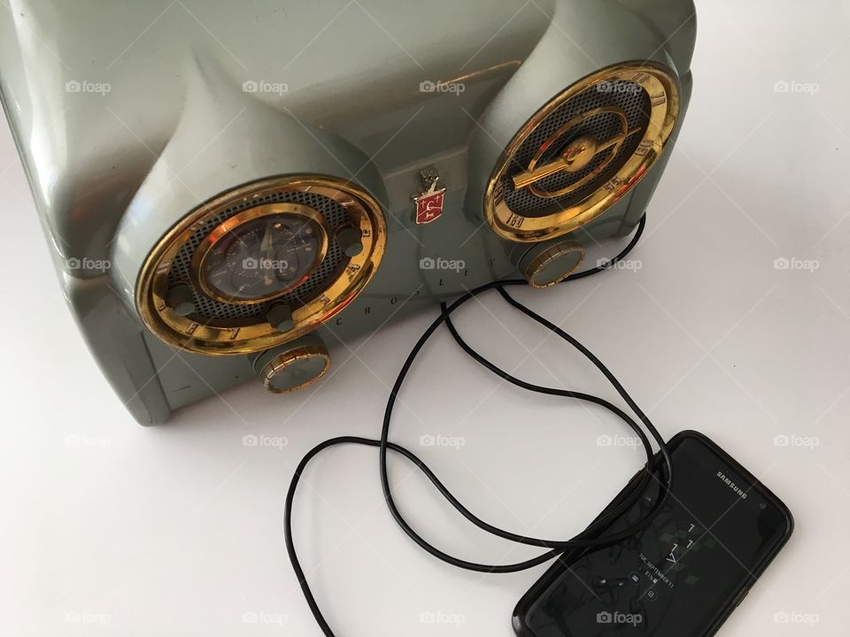 Old Meets New: A 1953 Crosley Clock Radio with an auxiliary plug connected to and playing music from a cell phone 