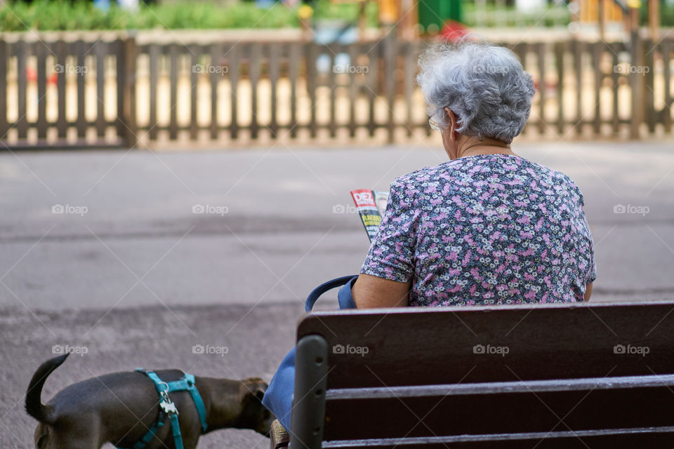 Elderly woman sitting in a street bench