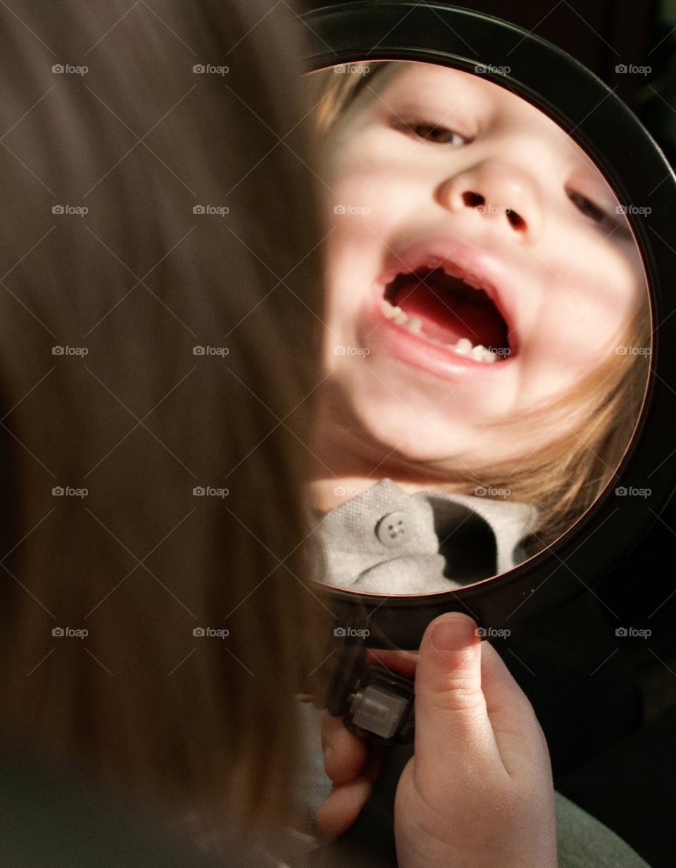 Little girl looking at her missing teeth in a mirror 