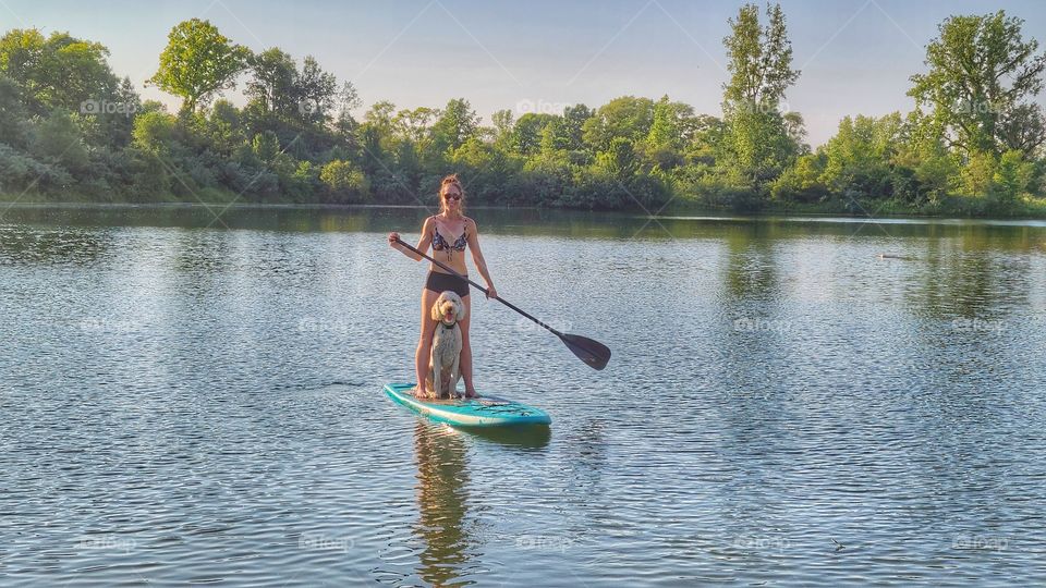 beautiful woman paddleboarding with dog