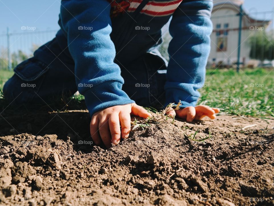 View of boys hands on mud