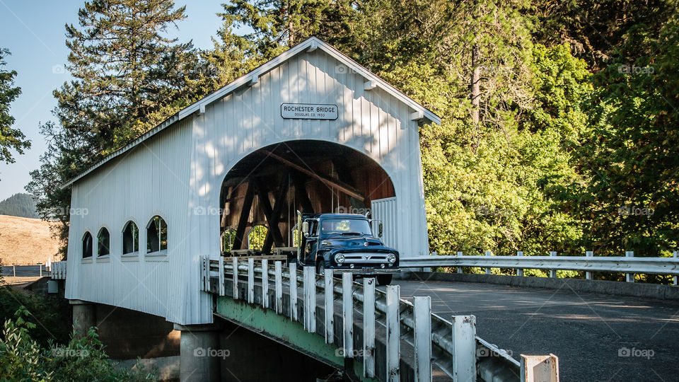 Old truck driving through covered bridge