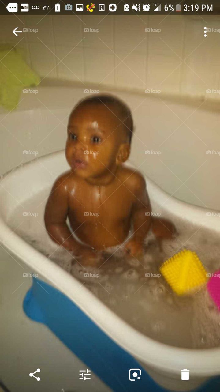 Happy baby in tub take a bath with good caring soft washing body and hair