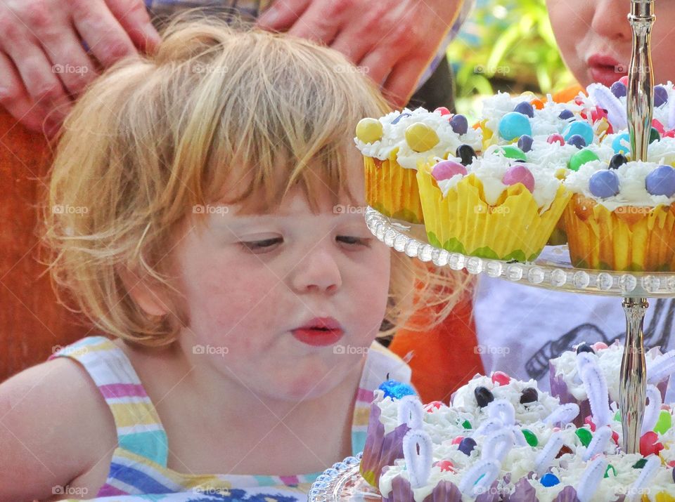 Cupcake Birthday Wish. Little Girl Making A Birthday Wish With Colorful Cupcakes
