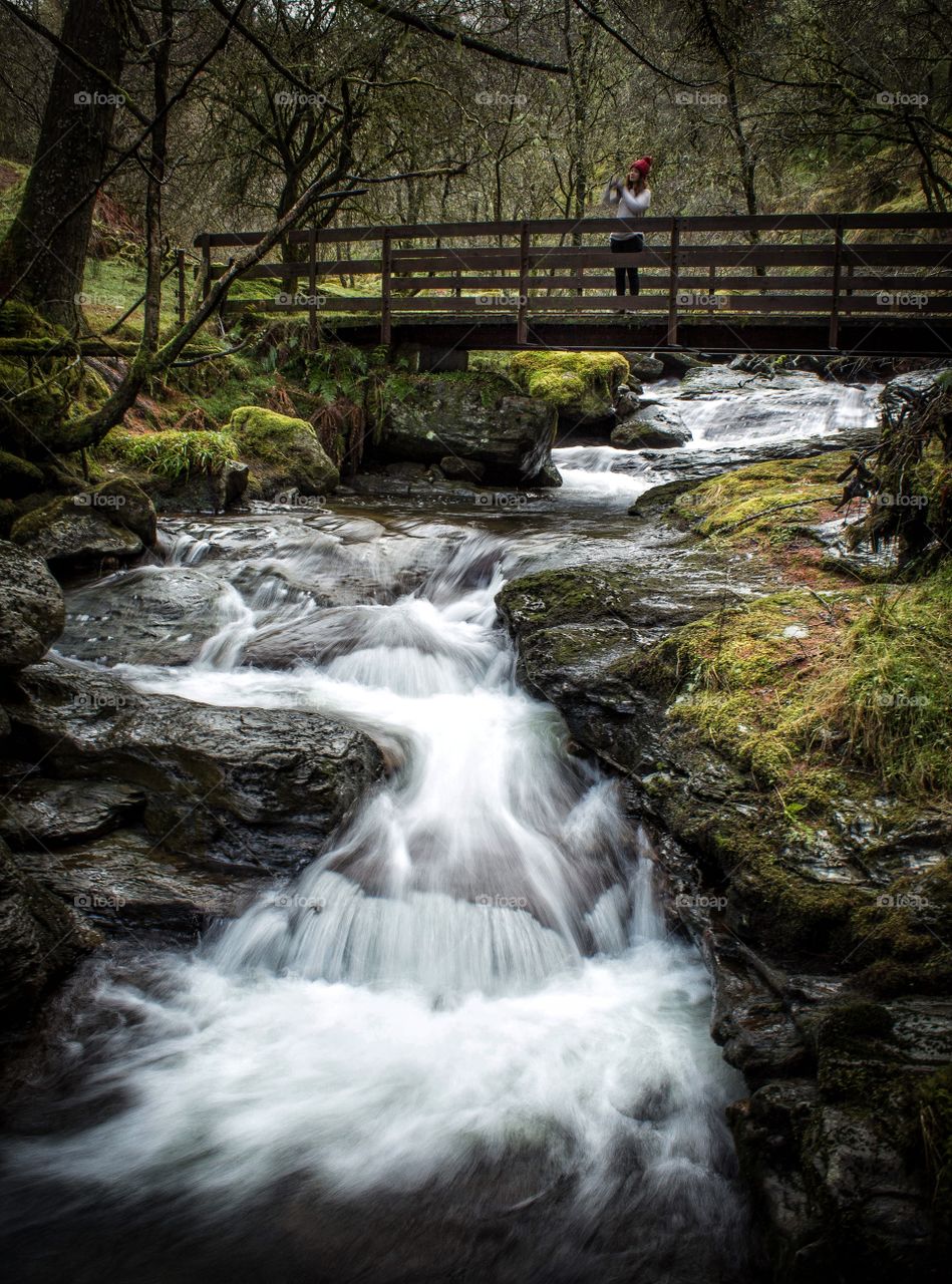 A girl watches over a waterfall. 