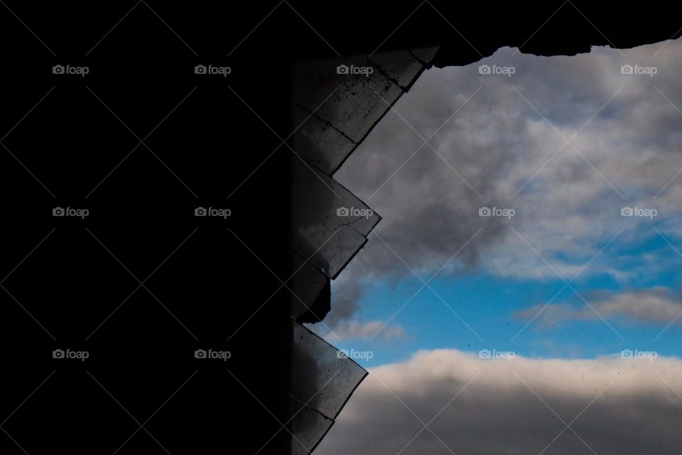 Nombre: Vidrio roto. Como si fuera un óleo. El Vidrio roto funciona como un marco. impacta el cielo azul y las nubes bien marcadas. el Vidrio delineado. altos contrastes.