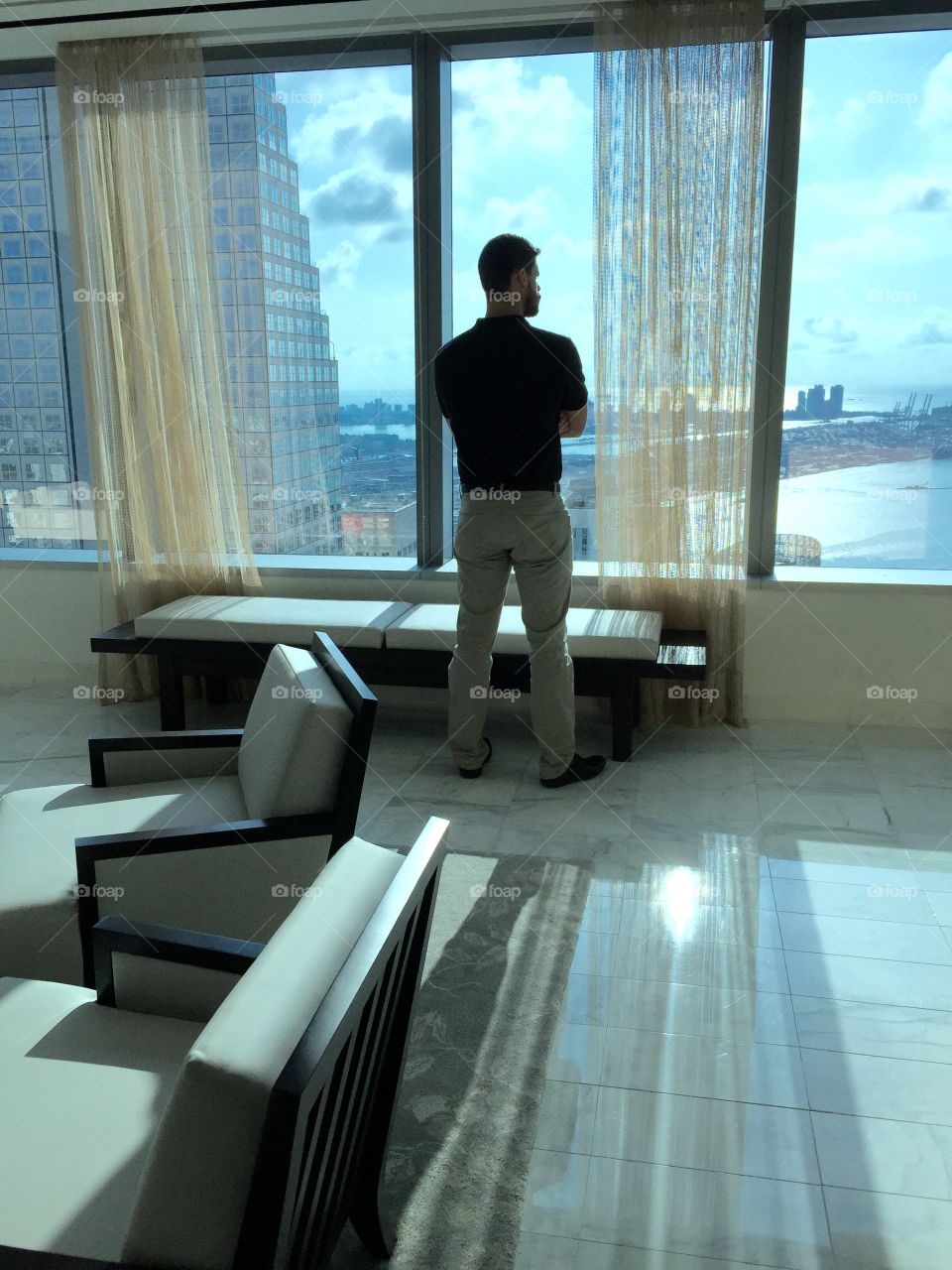 Contemplation . Young man standing by panoramic window in office