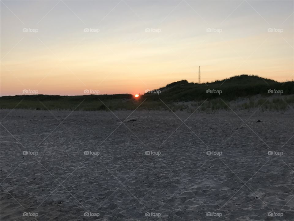 Sunset in crescent of sand dunes.