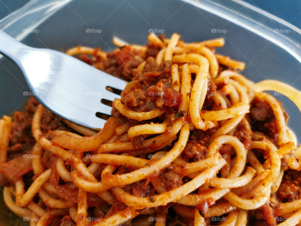 Spaghetti bolognese with fork in a plastic box.