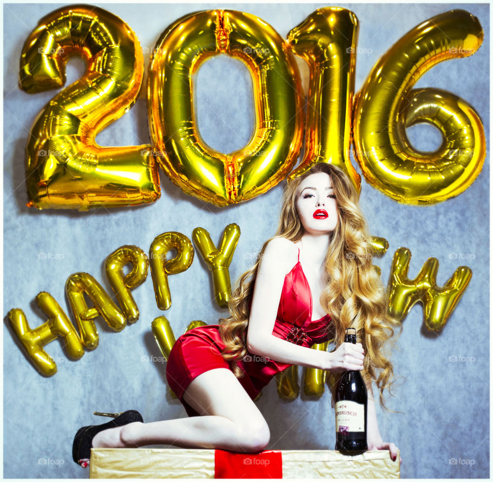 Beautiful woman with champagne bottle in front of Happy New Year text