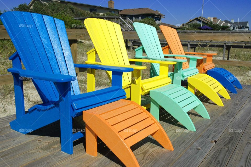 Colorful Adirondack chairs at the beach.   