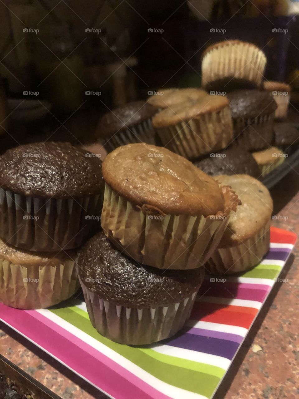 A countertop picture of muffins and cupcakes stacked in delicious delightful