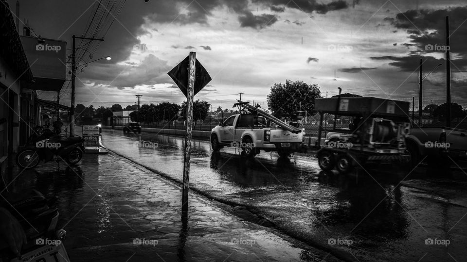 Rua molhada de chuva. Veículos, imagem em preto e branco.