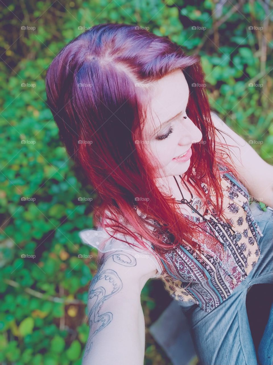 Downward perspective of purple and red hair, hippie style shirt out in nature. light exposure.