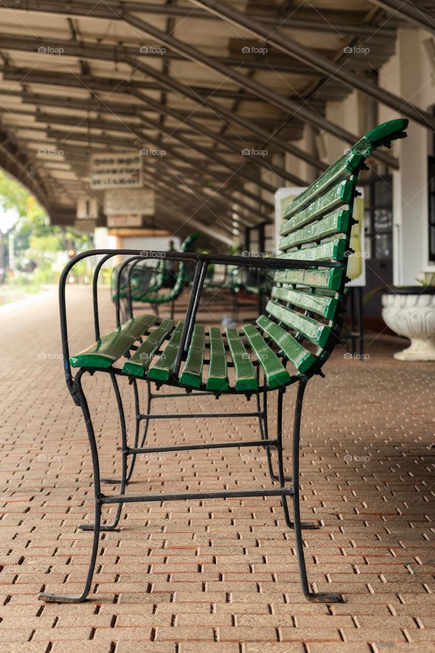 Out door bench at a railway station made of wrought iron and wood.