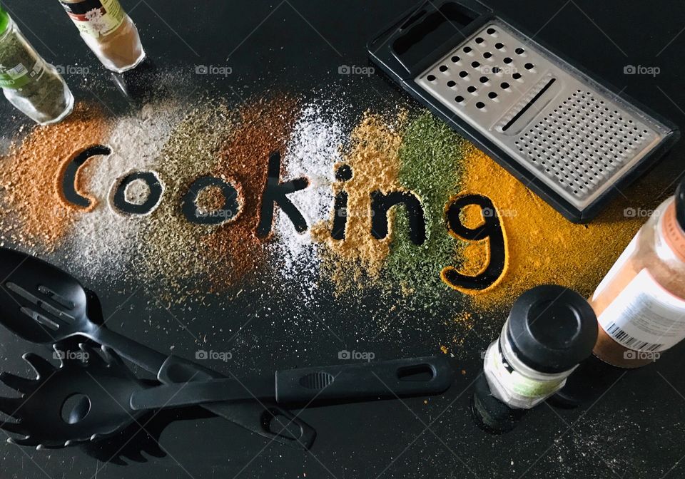 The word Cooking written in spices with kitchen utensils around it