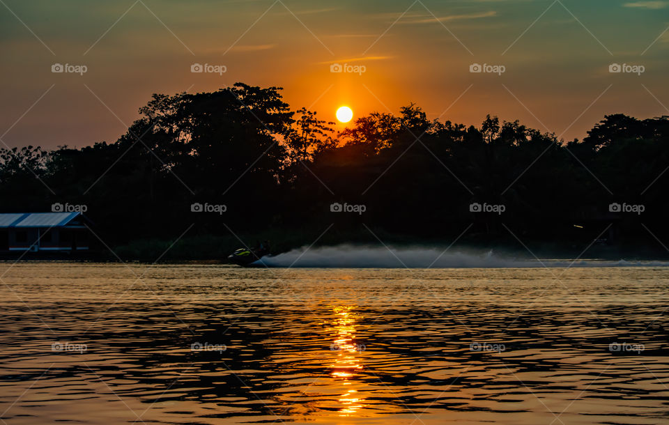 Tourists drive the Jet Ski and the sunset light in Khwae Noi river at Kanchanaburi Thailand .December 2, 2018