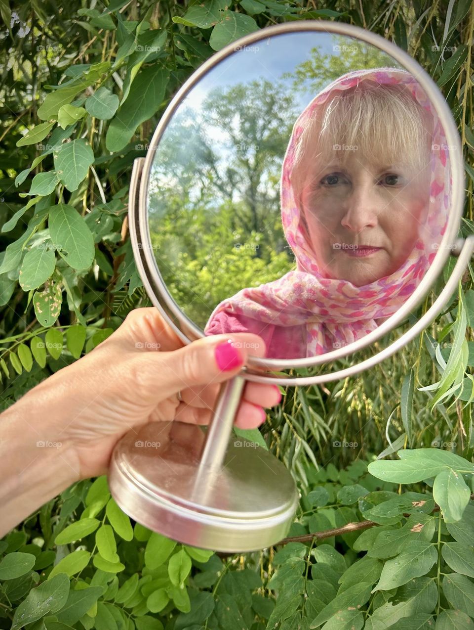 Selfie reflection of a blonde woman wearing a pink scarf 