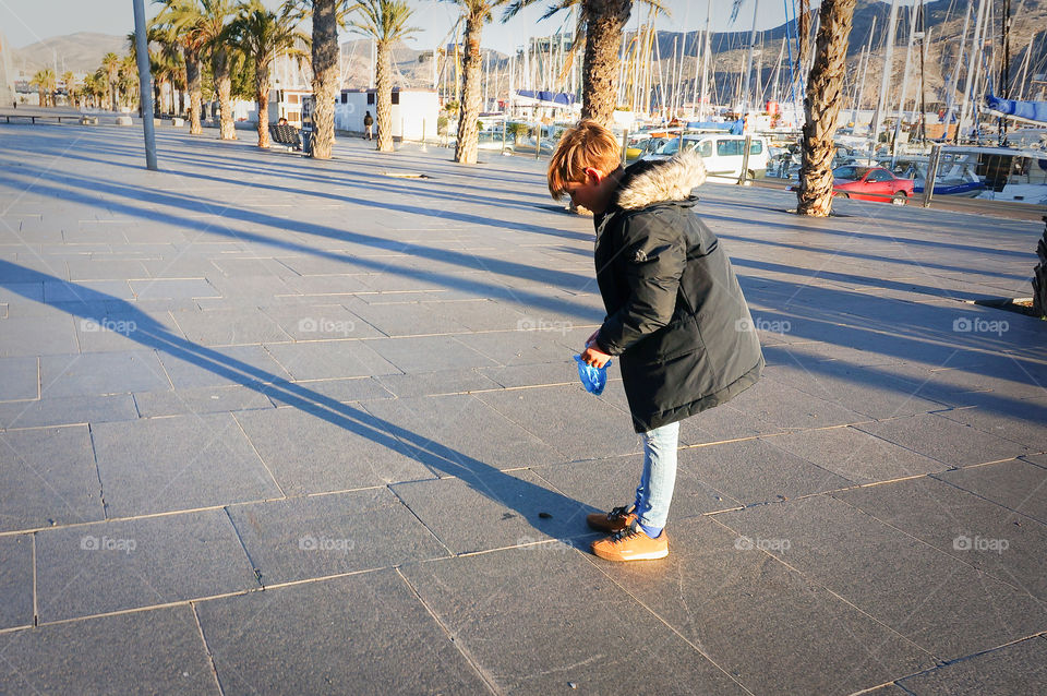 11 yrs old boy cleaning his dog’s poo on the street of a city