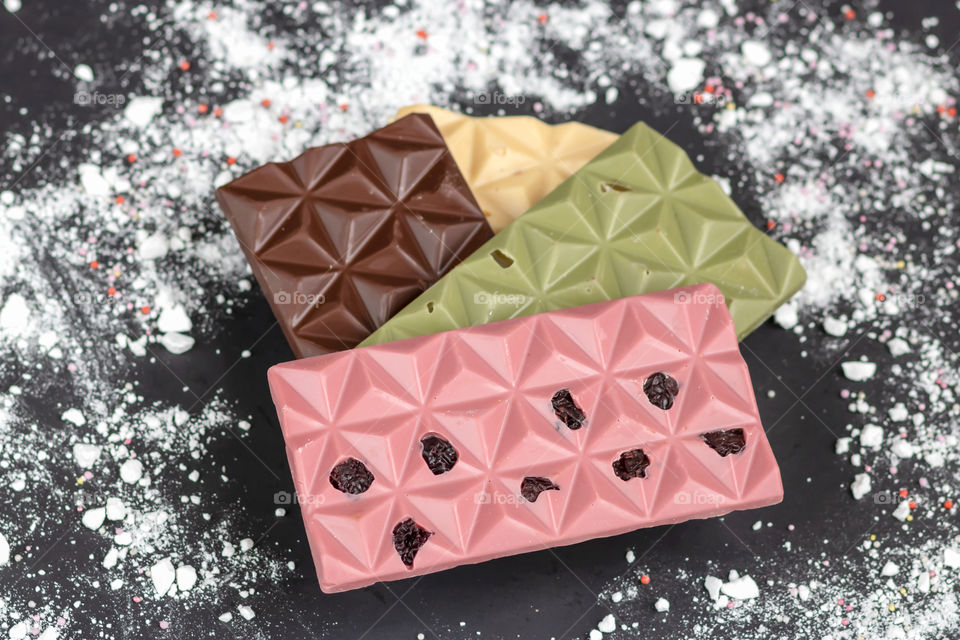 Closeup view of assorted handmade raw chocolate bar with dried fruits, matcha tea, spice and vanilla.