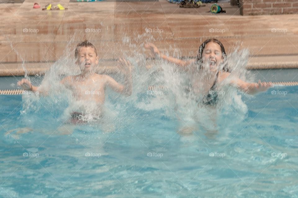 Brother and sister jumping for mom in the pool so she can shoot action photos with motion 